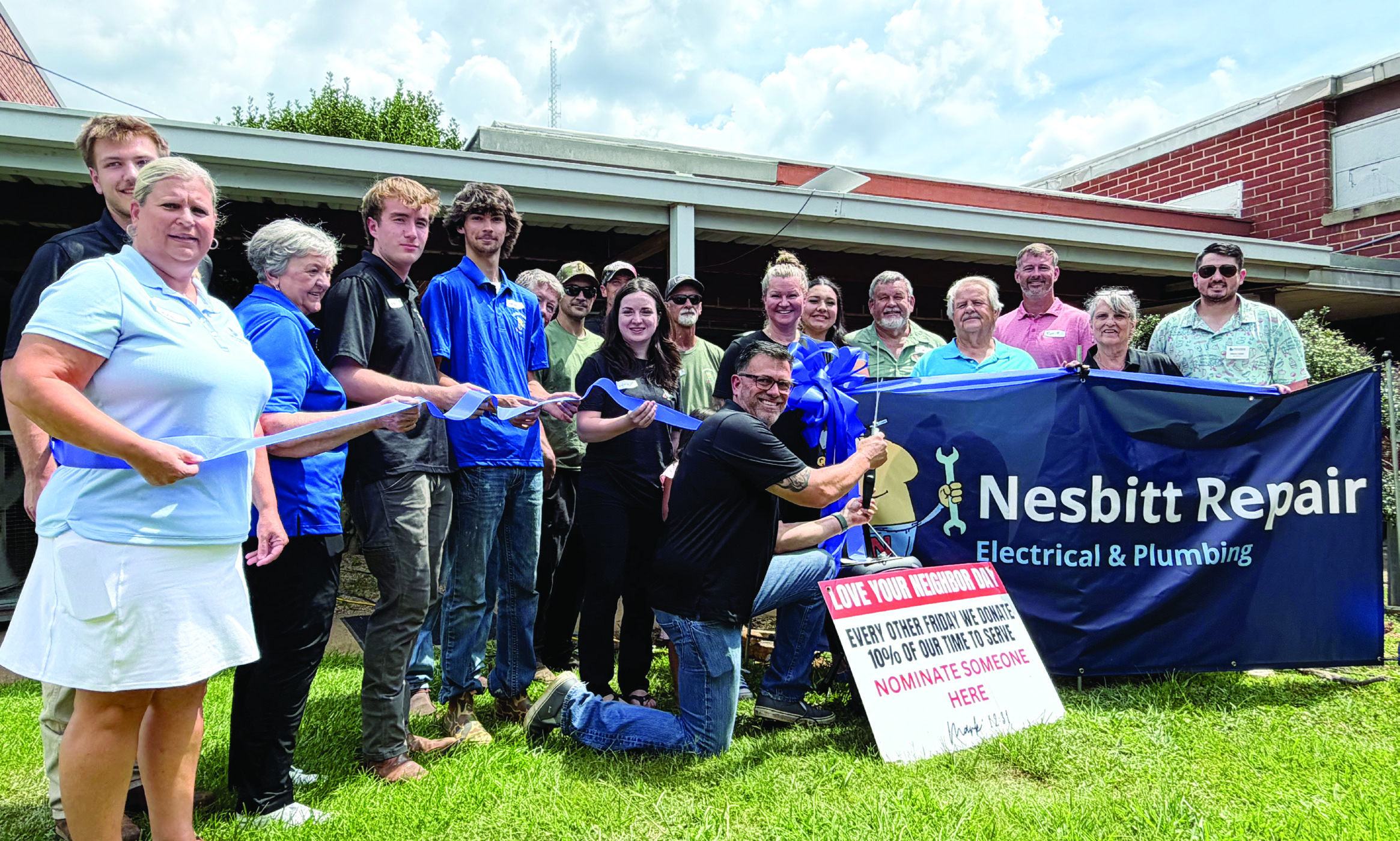Carlos Campos (kneeling) prepares to cut the ribbon July 10, to officially reopen Nesbitt Repair, an existing business that he and his wife, Chantel, purchased early this year from its founder, Frank Nesbitt. SKYLA MORRIS/Staff