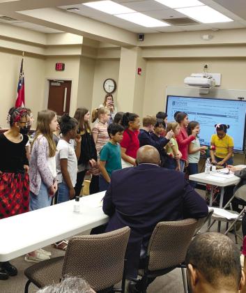 Third graders play xylophones as fourth and fifth grade prepare for to sing. Fourth and fifth graders sing two songs for the board while facing a large audience of parents and staff.
