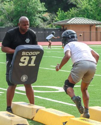 GCHS defensive coordinator Orus Lambert coaches up a pair of Tigers' defensive lineman during position drills on Monday. LANCE MCCURLEY/Staff