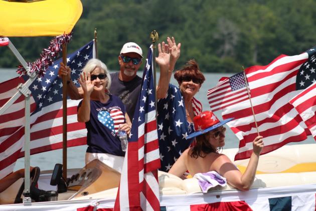 Participants in Joe Williamson's boat wave to spectators as American flags fly in the background. LANCE MCCURLEY/Staff