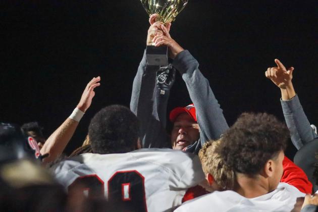Morgan County head coach Clint Jenkins hoists the trophy as he and players celebrate after defeating Harlem. LANCE MCCURLEY/Staff