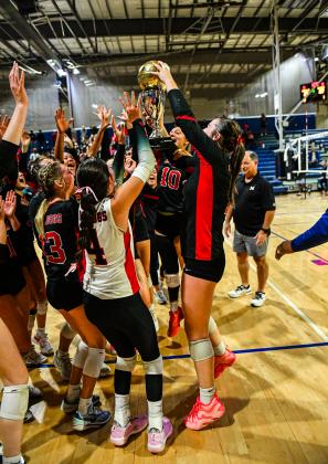 Members of the Morgan County volleyball team celebrate with the championship trophy after defeating Ringgold in the Class AA state title match on Oct. 30. CHARLES JORDAN/Staff