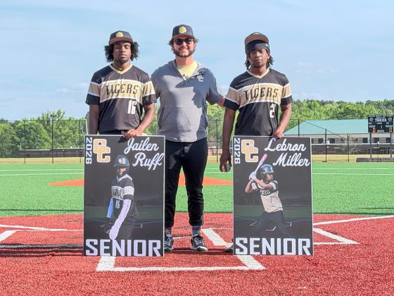 Greene County seniors Jailen Ruff (left) and LeBron Miller (right) pose for a photo with head coach Brad Evans (center) before the regular-season finale against Central Gwinnett on April 13. CONTRIBUTED