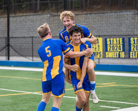 LOA seniors Austin Dell (5) and Garrett Griffin (6) celebrate with sophomore teammate Poli Medrano (15) after he scored the game-winning goal against Echols County on April 29, sending the defending state champion Titans back to the Elite Eight. SKYLA MORRIS/Staff