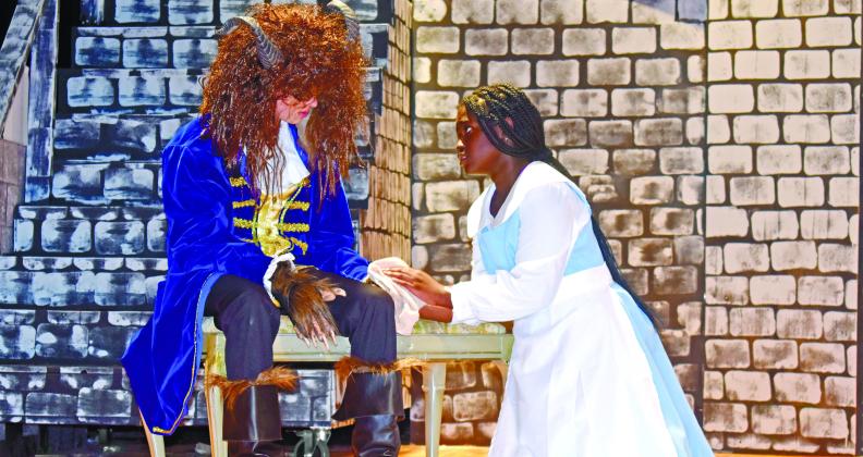 After Beast, played by Avry Shorter, is injured by wolves, Belle, played by Kenzie Nelson, cleans his paw.