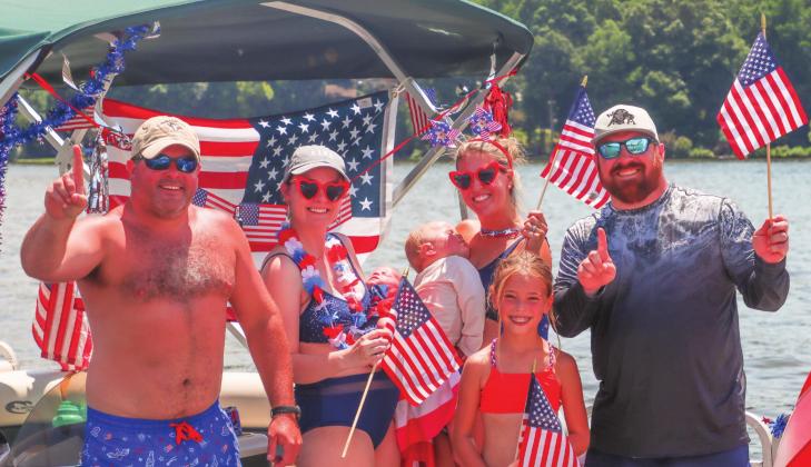Matt Massey (left) poses with others aboard his pontoon. Massey’s vessel won the award for the best-decorated boat at this year’s parade.