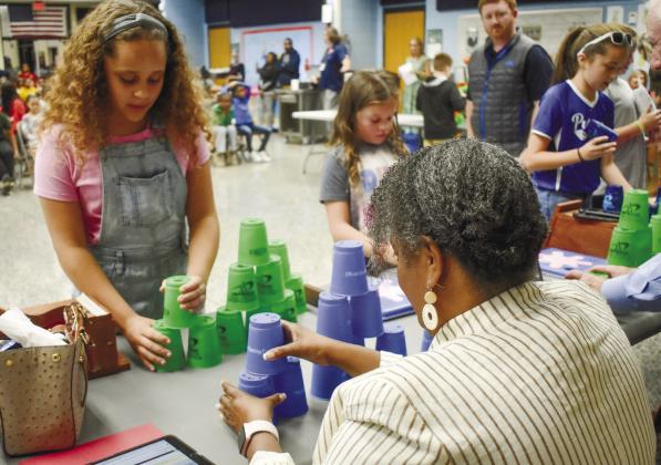 A Speed Stack Club member shows board member Simone Jones how to stack the cups. BAILEY McCULLY/Staff