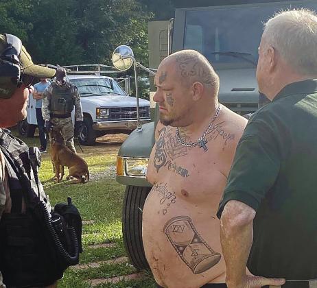Andy Kirk Davis, center, being held by Putnam County Sheriff’s Lt. Harry Luke, right, is questioned by Butts County Sheriff’s detectives outside Davis’ Putnam County home in 2020. CONTRIBUTED/PCSO