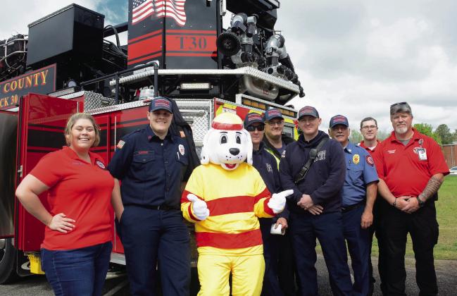 Members of the Putnam County Fire Department line up beside their mascot, “Sparky,” who posed all day with egg hunters while parents took photos.  IAN TOCHER/Staff
