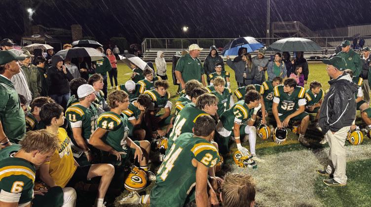 With steady rain falling, Gatewood head coach Jeff Ratliff (right, black jacket) addresses his team at midfield after a disappointing 30-17 loss last Friday to the visiting Windsor Academy Knights, from Macon.