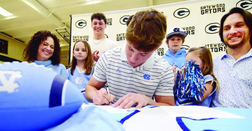 Surrounded by his family, including mother Christine and his father, Dan, Evan Bennett put pen to paper on his commitment contract with the University of North Carolina last Wednesday in Eatonton. IAN TOCHER/Staff