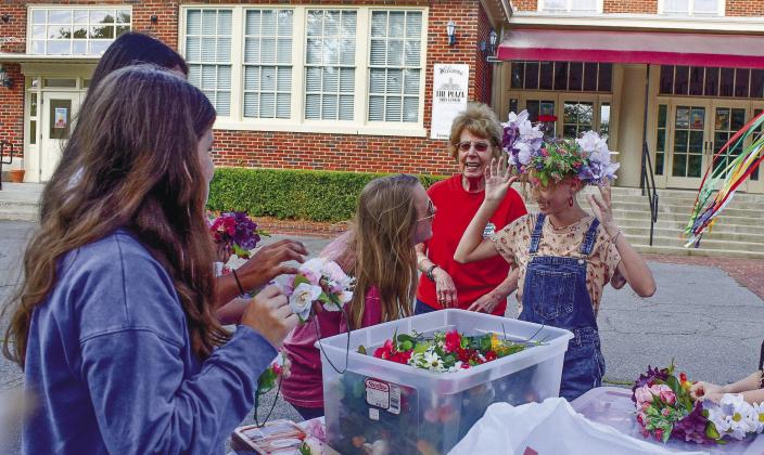 Abigail Hildreth tries on a flower crown she just made, Jade Mullis is having a close look to make sure it fits, and volunteer Janet Kelhoffer (behind them) is talking to the other girls working on their flower crowns. LENA HENSLEY/Staff