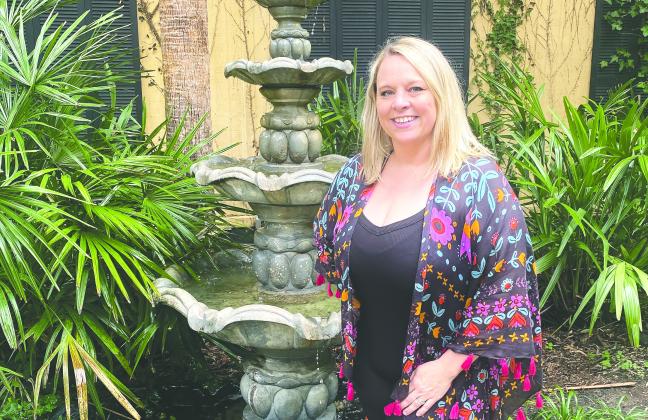 Nicole Green stands among the palms and fountain in the courtyard of The Palms on Main. MAUREEN STRATTON/Staff