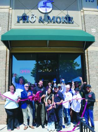 Pho & More co-owner Marino Graf (with scissors) stands with his wife, Summer, her father, John Nguyen, and the couple’s daughter while friends and employees help them celebrate during a ribbon-cutting ceremony hosted by the Eatonton-Putnam Chamber of Commerce. IAN TOCHER/Staff