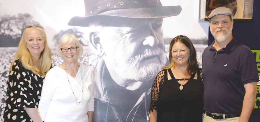 Tommie Kay (in glasses) is joined by daughters Heather (left) and Terri, plus son Jon in front of a large portrait of their late father, author Terry Kay, Saturday at the Georgia Writers Museum.