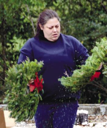 Putnam County VFW Commander Nikki Barker shakes stray needles from wreaths before laying them in tribute on Eatonton veterans’ graves. IAN TOCHER/Staff