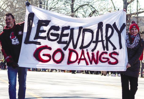 Bulldog fans walk down South Lumpkin Street with a sign celebrating the Bulldogs’ back-toback national titles before the parade. LANCE MCCURLEY/Staff