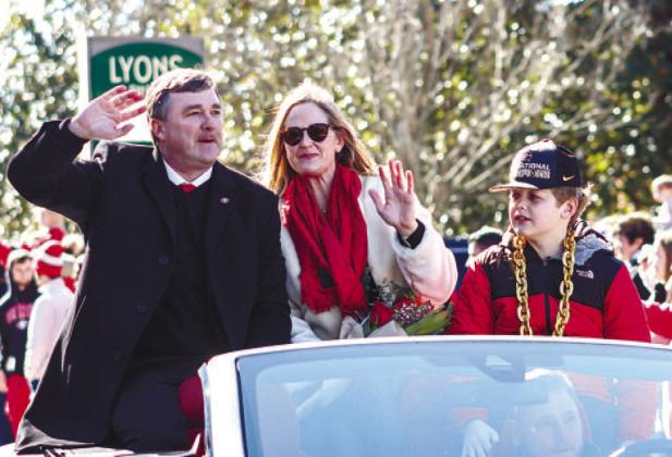 Georgia head coach Kirby Smart (left), his wife, Mary Beth (center), and their son, Andrew (right), ride in the back of a convertible while waving at fans during Saturday’s parade. LANCE MCCURLEY/Staff