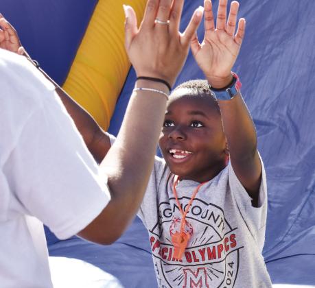 Trystan Mobley from Mrs. Butler’s classroom at Morgan County Primary School gets a pair of high fives after enjoying the bouncy house. (T. MICHAEL STONE/Staff)