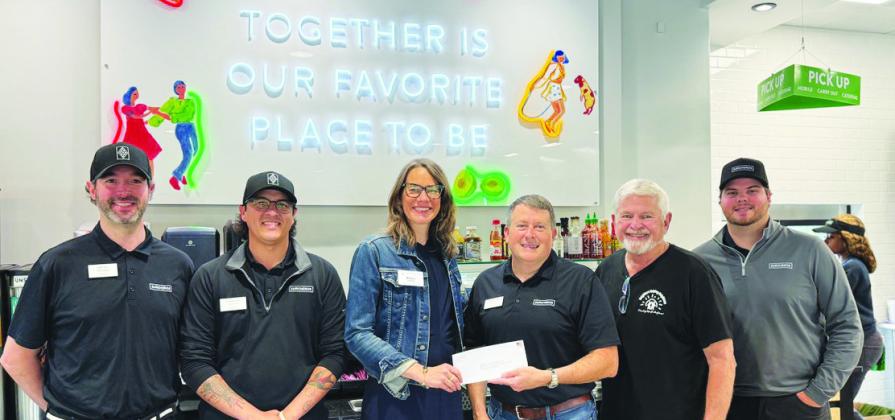 Neighbors Helping Neighbors Executive Director Allyn Rippin (center) accepts a donation from Surcheros owner Kyle Cullars, with several Surcheros employees standing by in support. CONTRIBUTED