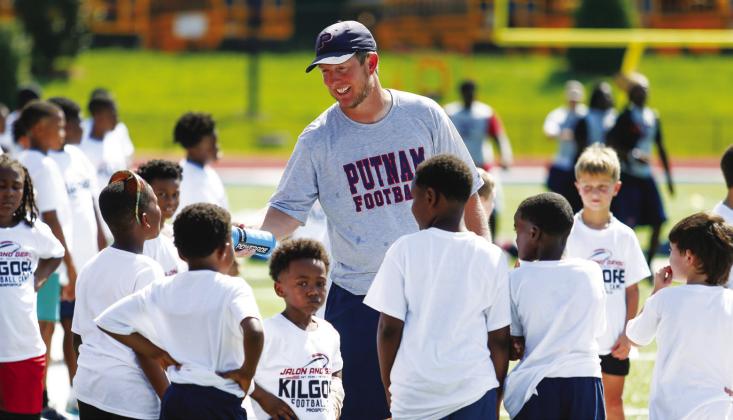 Current Putnam County head football coach Joel Harvin hands out water to campers during a break in the action. LANCE MCCURLEY/Staff