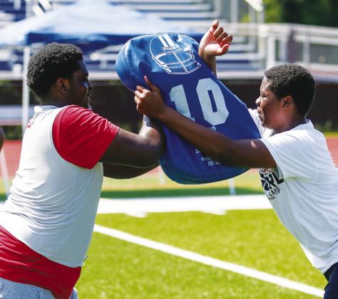 A Putnam County player (left) and a camper (right) work through a blocking drill during the camp. LANCE MCCURLEY/Staff