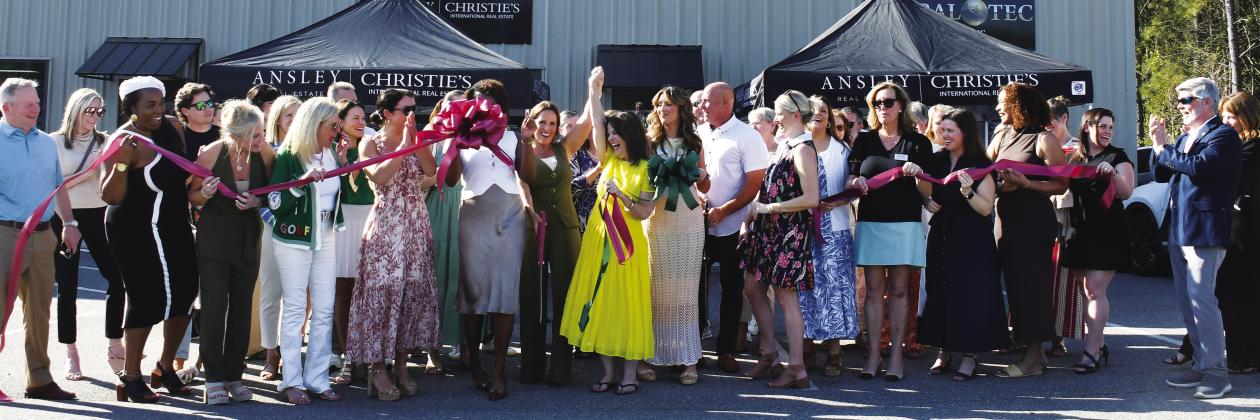 Adriana Velez (center with scissors) was joined by a large throng of business colleagues and well wishers last Thursday as she officially cut the ribbon to her new Ansley R.E.-Christie’s Int’l. business center in a joint ceremony co-hosted by Eatonton-Putnam Chamber of Commerce President Robbie King and Greene County Chamber of Commerce President Mika Mills (both, far right). IAN TOCHER/Staff