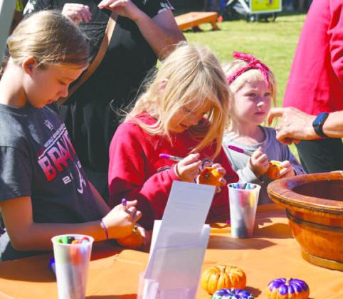 These young ladies are focused on the pumpkin decorating contest.