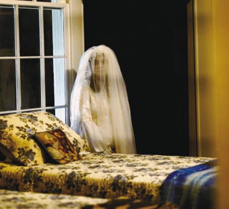 The actress playing Sylvia stands by the bedroom window on the second floor of Panola Hall, dressed in her trademark white wedding gown. GENE GARCIA/Contributed