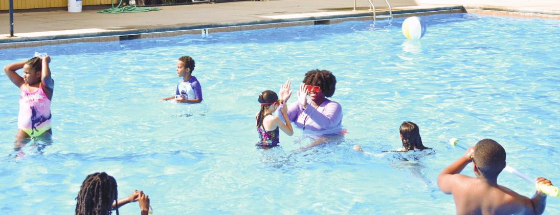 Camp instructor Rakeena Griffin high-fives third-grader Skylar Bridges, who just successfully swam up to her covering some distance in water.