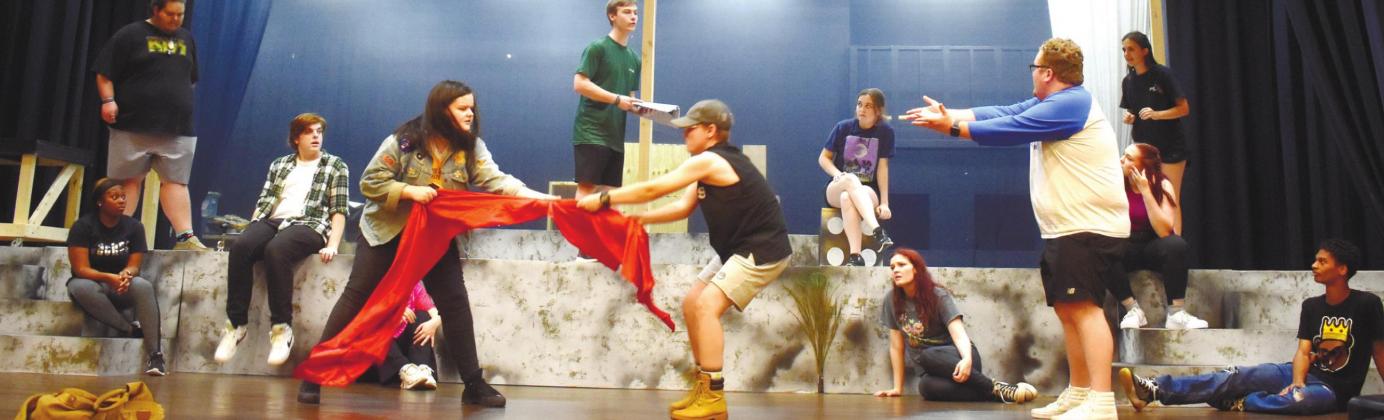 The “Godspell” cast practices a scene where conflict is shown through tug of war by the red curtain. BAILEY BALLARD/Staff