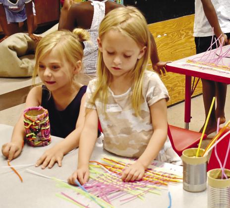Josie Holder and Cadence Reid weave pipe cleaners together to decorate their pencil holders. LENA HENSLEY/Staff