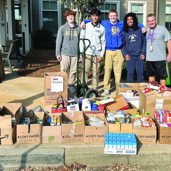 LOA high school students and their weight training teacher Tom Imhoff (far right) collaborated to help load the trucks with several boxes of food for the local pantry. CONTRIBUTED