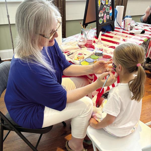Five-year-old Evelyn Mallinson gets her face painted with a pink flower. (EMMA CLAUSE/Staff)