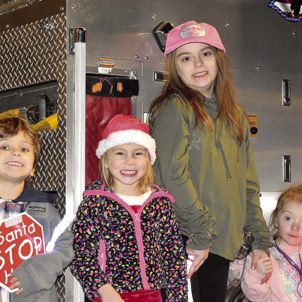 Some of Greensboro’s youngest are all smiles for Christmas while posing in front of a fire truck. HANNAH BARRON/Staff