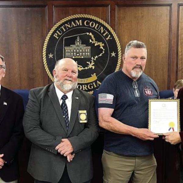 L-R: Newly elected District 1 Commissioner Tom McElhenney, District 2 Commissioner Daniel Brown, Commissioner Jeff Wooten of District 4, retiring Putnam County Fire Department Battalion Chief Michael Alford, County Chairman Bill Sharp, and District 3 Commissioner Dr. Steve Hersey stepped forward for Alford’s retirement recognition. IAN TOCHER/Staff