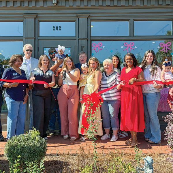 Alecxandra Hammond (middle) cuts the ribbon for the grand opening of May Lane Boutique, alongside local officials, family, and friends. SKYLA MORRIS/Staff