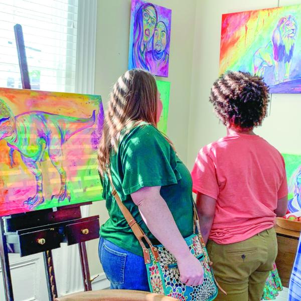Two attendees view “Chromatic King” (right) that depicts a lion looking out beyond where it stands.