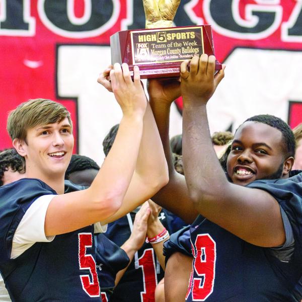 Morgan County seniors and football co-captains Davis Strickland (left) and Ja’mari Mundy hoist the Team of the Week trophy high, signifying the team’s selection by Fox 5 Atlanta’s “High 5 Sports” show. SKYLA MORRIS/Staff