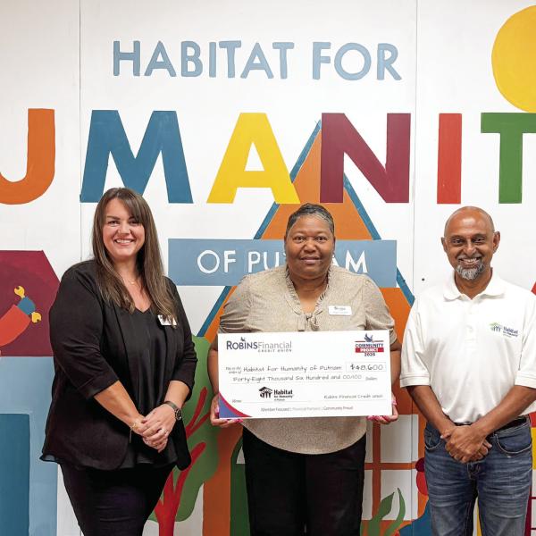 Habitat for Humanity of Putnam Executive Director Murali Thirumal (right) accepts a $48,600 grant check from representatives of Robins Financial Credit Union. CONTRIBUTED