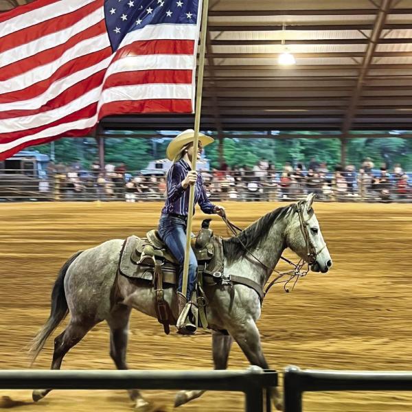 A rodeo performer carries the American flag during the presentation of flags. (CONTRIBUTED)