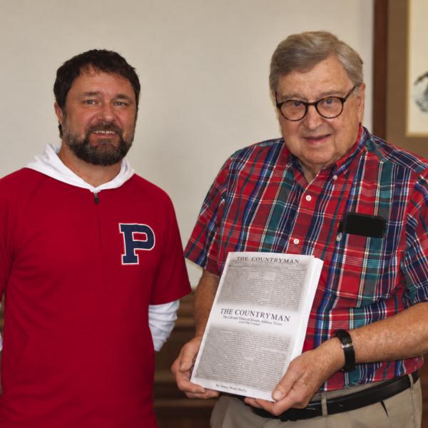 E-PCHS president Jim Marshall presents a copy of The Countryman to Smith Communications’ graphic designer Brandon Park, who did the layout and design work . A. MARK SMITH/Staff