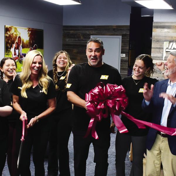 Greene County residents Dana and Dr. Pablo Santamaria (center, with scissors and bow) opened InMotion Wellness initially based on Pablo’s exposure to the benefits of targeted, assisted stretching after undergoing an operation to correct a painful back condition. IAN TOCHER/Staff