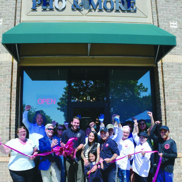 Pho & More co-owner Marino Graf (with scissors) stands with his wife, Summer, her father, John Nguyen, and the couple’s daughter while friends and employees help them celebrate during a ribbon-cutting ceremony hosted by the Eatonton-Putnam Chamber of Commerce. IAN TOCHER/Staff