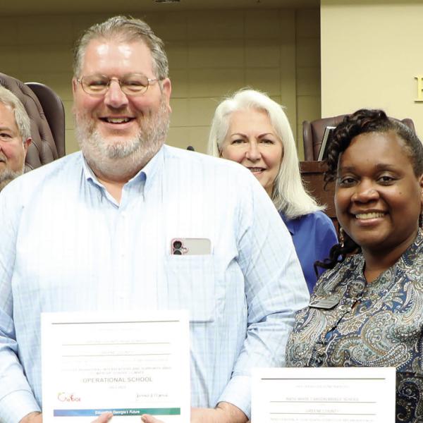 GCPS Principal Ashlie Miller, (left) GCHS Assistant Principal Dr. James Meneguzzo, (center left) and CMS Principal Tanisha Wright (center right) receive their schools’ PBIS recognitions from the state at Thursday night’s BOE meeting from Assistant Superintendent Dr. Rotonya Rhodes (right) along with the BOE members. (CONTRIBUTED)
