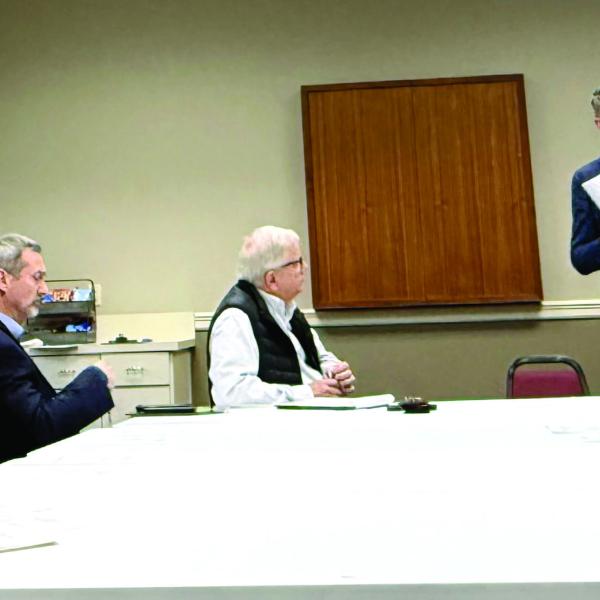 Joel Wiggins (standing), managing partner of the Southern Group of Georgia and a representative of the C-PACE Alliance, addresses members of the Lake Oconee Area Development Authority last Thursday at Farmers &amp; Merchants Bank on Lake Oconee Parkway. Melody Echols, program administrator with Peach State C-PACE, is seated at left. IAN TOCHER/Staff