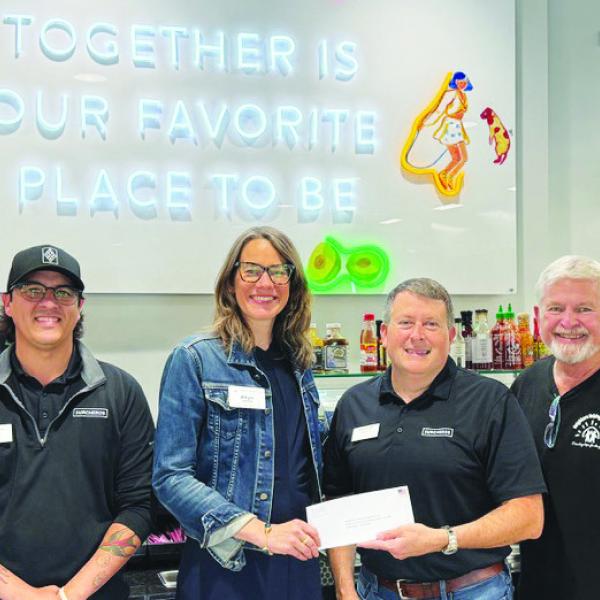 Neighbors Helping Neighbors Executive Director Allyn Rippin (center) accepts a donation from Surcheros owner Kyle Cullars, with several Surcheros employees standing by in support. CONTRIBUTED