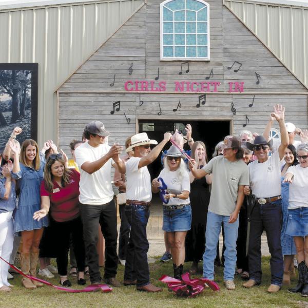 Kathy Rainey (with scissors) cut the ribbon Oct. 8, as she and her husband, Mike Rainey (two to her left, waving) welcomed about 30 well-wishers to their Briarpatch Farm on Pea Ridge Road in Putnam County. In addition to being a working cattle farm, the barn behind them at Briarpatch Farm serves as an event space several times each year.