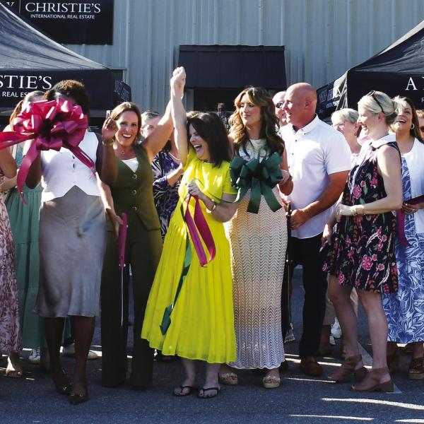 Adriana Velez (center with scissors) was joined by a large throng of business colleagues and well wishers last Thursday as she officially cut the ribbon to her new Ansley R.E.-Christie’s Int’l. business center in a joint ceremony co-hosted by Eatonton-Putnam Chamber of Commerce President Robbie King and Greene County Chamber of Commerce President Mika Mills (both, far right). IAN TOCHER/Staff