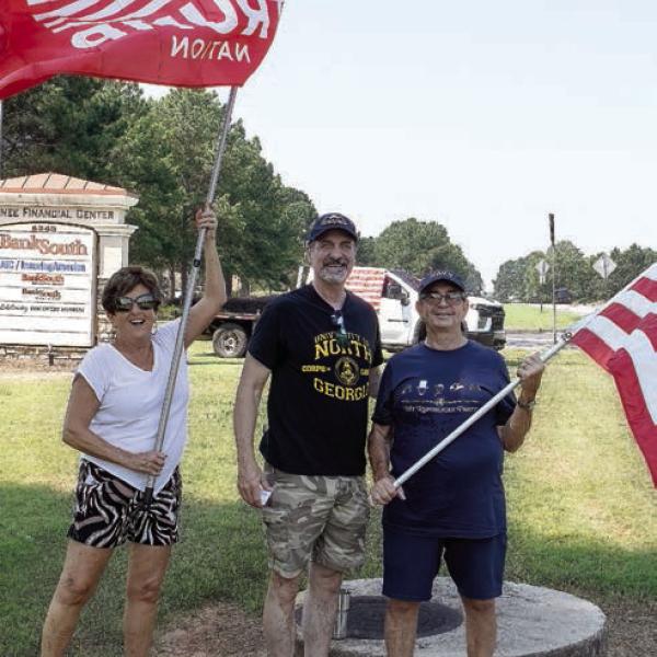 Despite wind and high temperatures, the flag continued to hold high with Gail Hartley, David DuBois and David Lollis. (LEIGH LOFGREN/Staff)